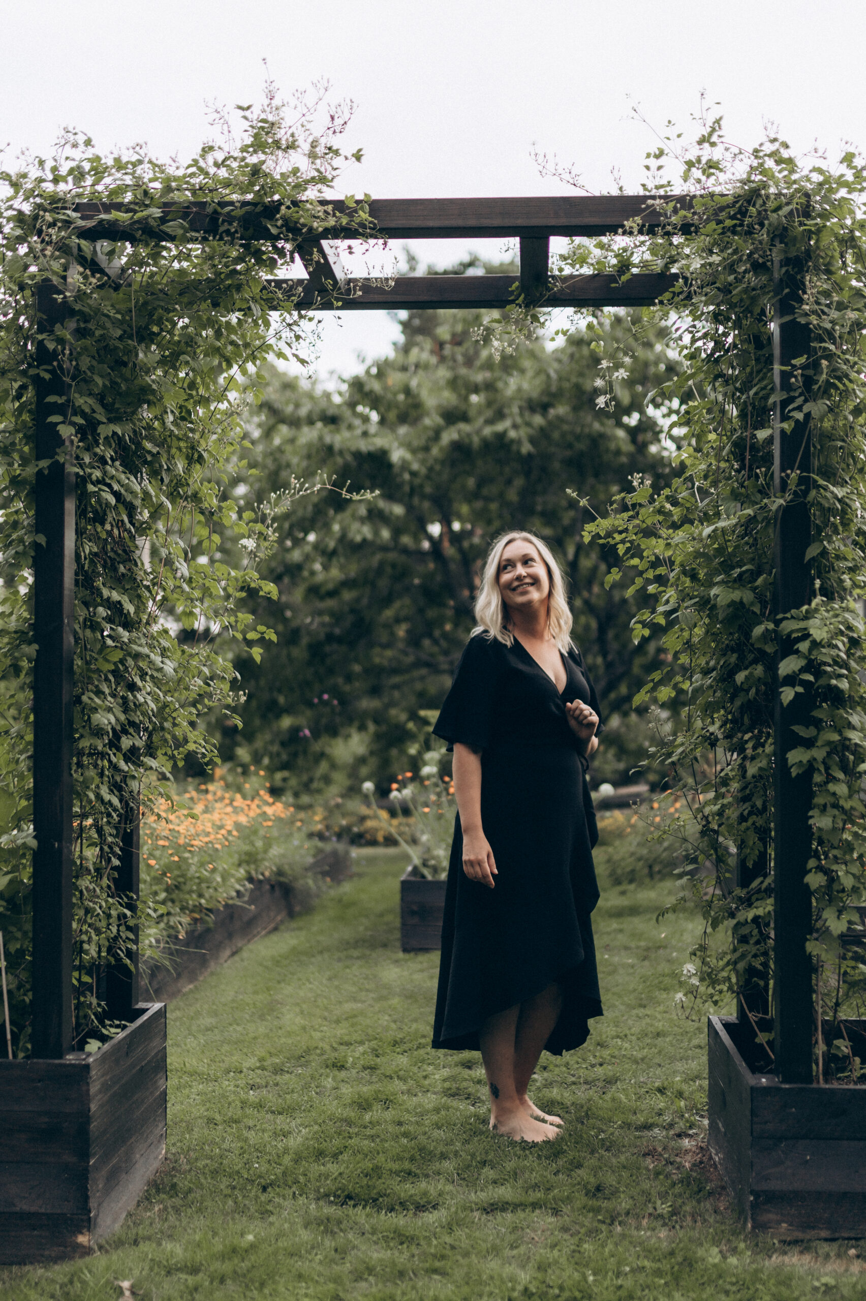 Trädgårdsarkitekt Valeria Martinsson i en grönskande portal i en trädgård.