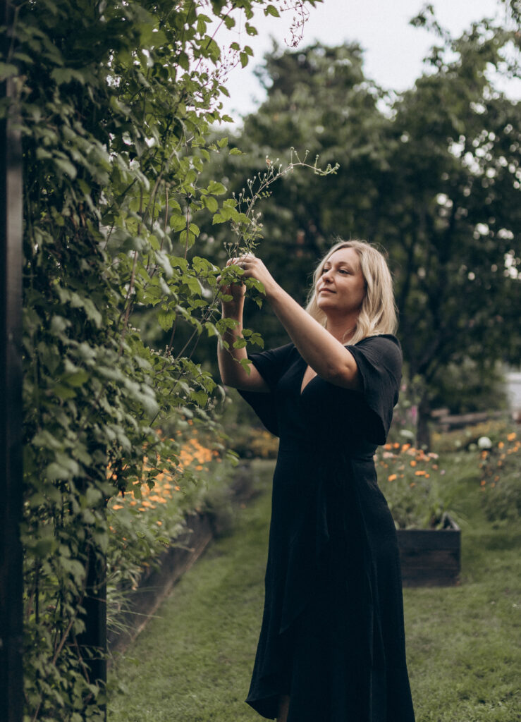 Trädgårdsarkitekt Valeria Martinsson i trädgård och sköter en buske.