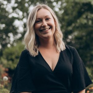 Trädgårdsarkitekt Valeria Martinsson leende i svart klänning i trädgård.